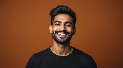 Fototapeta premium People positive emotions concept. Studio waist up of young happy smiling broadly Hindu man standing in centre isolated on brown background wearing black casual t shirt looking straight at camera photo