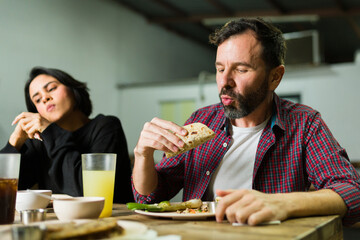 Bearded man looking excited before biting a taco at a taqueria while eating out in a taqueria with...