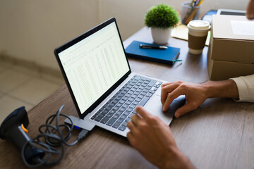 Entrepreneur using laptop and spreadsheet software for managing online sales and ecommerce logistics