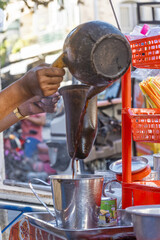 Man pours boiling water over a cloth filter containing ground coffee at a cafe in Phnom Penh
