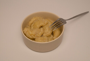 A plate of traditional varenyky on a white table with a fork.