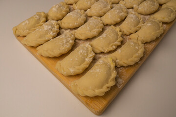 Ukrainian potato varenyky z kartoplyu, lined up on a flour-dusted wooden board.