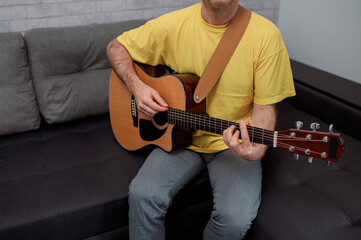 Obraz premium man guitarist playing guitar at home. Relaxing and sitting on sofa
