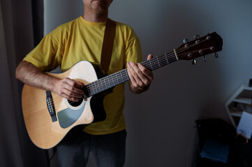 Obraz premium Guitarist on acoustic guitar playing melody in studio. Close up musician instrument