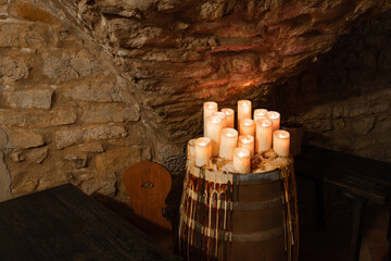 Cozy rustic room with stone walls, wooden barrel, and glowing candles.