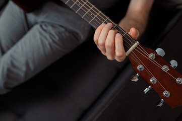 Obraz premium man guitarist playing guitar at home. Relaxing and sitting on sofa