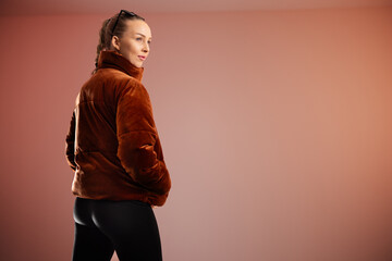 Obraz premium Young woman wearing brown coat posing in modern and clean studio setting