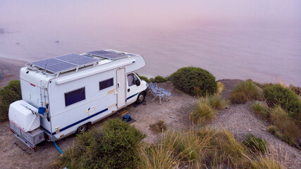 Caravan with solar panels on roof on coast, Spain. Aerial view.