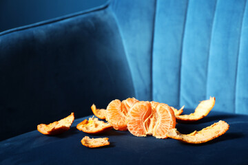Fresh peeled tangerine on dark blue armchair
