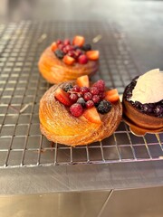 Round croissant with fruits on wire rack at bakery