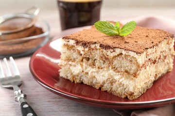 Delicious tiramisu with mint on light wooden table, closeup