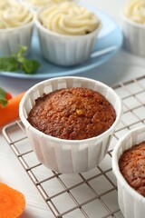 Delicious carrot muffins and fresh vegetable on white wooden table, closeup