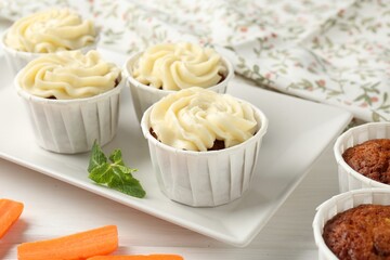 Delicious carrot muffins and fresh vegetable on white wooden table, closeup