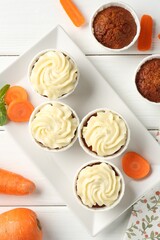 Delicious carrot muffins with fresh vegetables and mint on white wooden table, flat lay