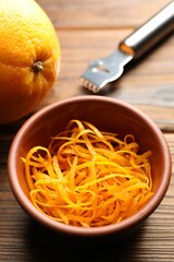 Orange zest, zester tool and fresh fruit on wooden table, closeup