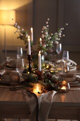 Christmas celebration. Festive table setting with dishware, glasses and decor in room