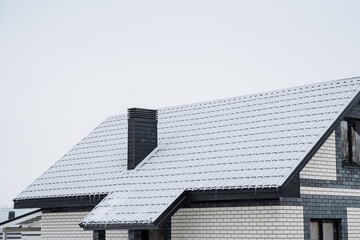 The roof of a house is currently blanketed in a fresh layer of white snow, creating a picturesque...