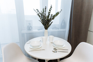 There is a beautifully arranged table that features elegant plates, various utensils, and a lovely vase filled with fresh flowers placed gracefully on it, creating a charming dining atmosphere