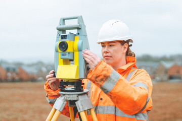 Woman Surveyor working with equipment to measure land in a rural area during an overcast day