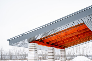 This captivating design features an elegant wooden canopy supported by striking stone pillars, set...