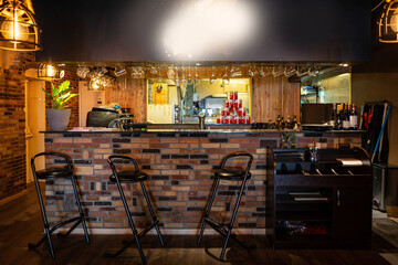 Half-lighted hall in a loft style restaurant open kitchen background.