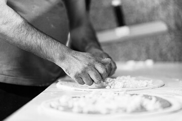 Hands preparing a pizza putting cheese mozzarella on pizza