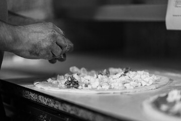 Hands preparing a pizza putting cheese mozzarella on pizza
