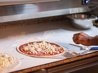 Hands preparing a pizza putting cheese mozzarella on pizza