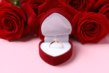 Beautiful shiny gold wedding ring with big diamond gemstone in rich velvet box with red roses on...