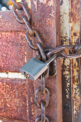 Old metallic door with a padlock and a rusty chain at rural Mexico, details close-up.