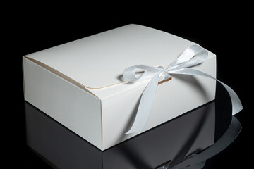 White gift box decorated with a white bow on an isolated black background with a clipping path