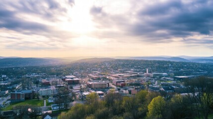 Fototapeta premium Golden Hour Cityscape: Aerial view of a town bathed in the warm glow of sunset, showcasing its architecture, lush greenery, and rolling hills in a picturesque landscape. 