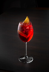 Red drink cocktail in a glass with citrus on a black background