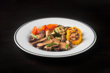 Meat with vegetables on a white plate on a black background