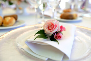 Beautiful table setting with tableware, flowers, accessories and beautiful rose for a party, wedding reception or holiday event. Photographed in ambiental light.