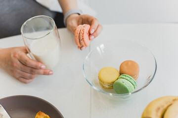 A person has breakfast with milk and macaroons