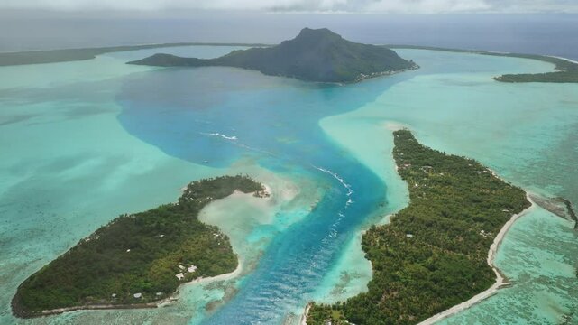 Breathtaking aerial view of Maupiti island in French Polynesia, showcasing the mesmerizing turquoise water channels weaving through lush greenery and a central volcanic peak. Remote wild nature travel