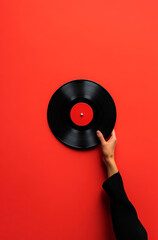 Obraz premium black vinyl record held by a hand against a bold red background, emphasizing the contrast and minimalistic design. It exudes retro vibes and celebrates music and vintage style
