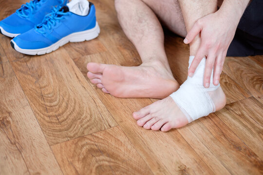 sportsman massaging his injured ankle after a sport accident - Powered by Adobe