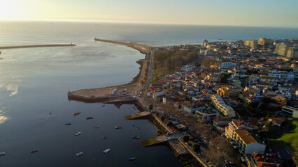 Vista capturando a deslumbrante paisagem do Porto e de Matosinhos, onde o Rio Douro encontra o Oceano Atlântico. A cena apresenta as areias douradas da praia de Matosinhos, 