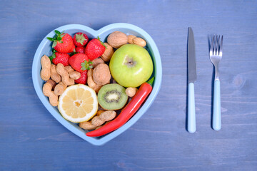 Heart shaped dish with vegetables isolated on blue wooden backgr