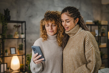 two female friends use mobile phone and have fun together at home