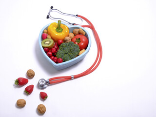 Heart shaped dish with vegetables and stethoscope isolated on white background