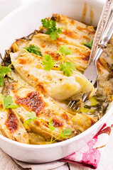Traditional Italian chicory gratinated with buffalo mozzorella and herbs served as closeup in a classical backing form