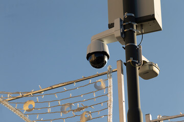 Surveillance cameras are securely mounted high on a tall pole at outdoor area. The scene emphasizes security, monitoring, and the integration of technology within urban and natural environments.