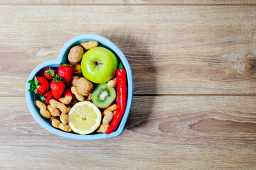 Heart shaped dish with vegetables isolated on wooden background