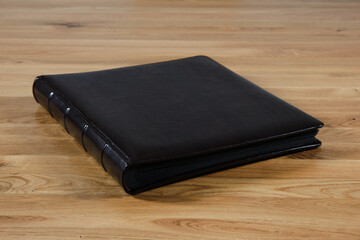 Traditional photo album, interleaved with parchment sheets, lying on a wooden table