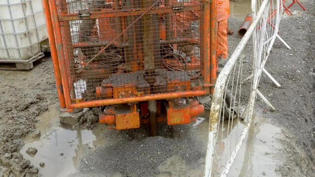 Construction crew uses small Pile rig auger drilling equipment in wet conditions at an urban site