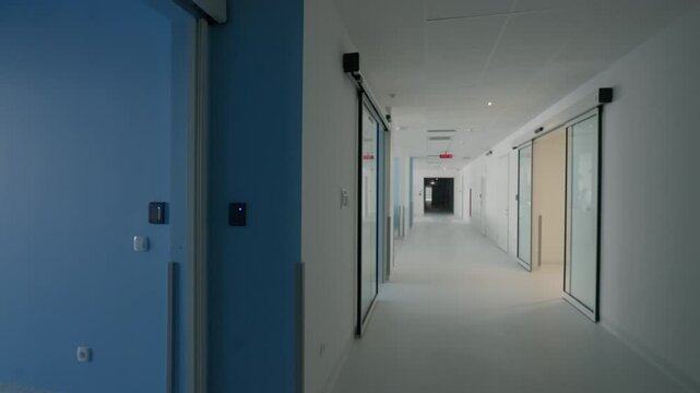 Modern hospital corridor with clean, bright design, featuring automatic sliding doors and blue accents on the walls. Concept of healthcare facilities and contemporary medical architecture