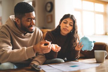 Couple discussing finances while planning budget with piggy bank in cozy living room during afternoon